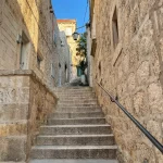 Vertikale Aufnahme einer engen Gasse mit Steinmauern und Treppen in Hvar, Kroatien
