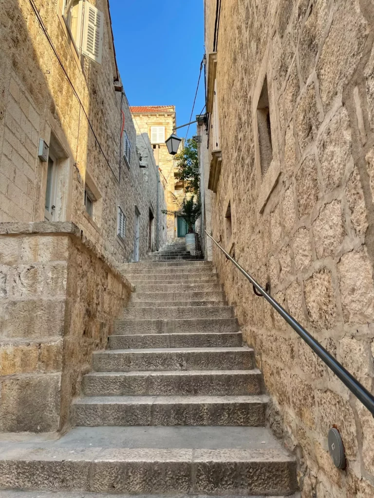 Een verticale opname van een smalle steeg met stenen muren en trappen in Hvar, Kroatië