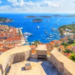 Sommerlandschaft an der Küste - Blick von der Festung auf den Stadthafen und den Yachthafen der Stadt Hvar auf der Insel Hvar an der kroatischen Adriaküste