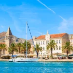 Sailing boat anchoring in Trogir town with historic buildings in background, Dalmatia, Croatia