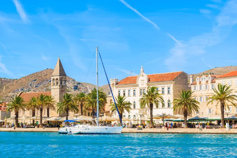 Sailing boat anchoring in Trogir town with historic buildings in background, Dalmatia, Croatia
