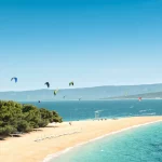 Uitzicht op de Gouden Hoorn op het eiland Brac in Kroatië. Kitesurfer en windsurfer op de achtergrond verlevendigen het schilderachtige tafereel.