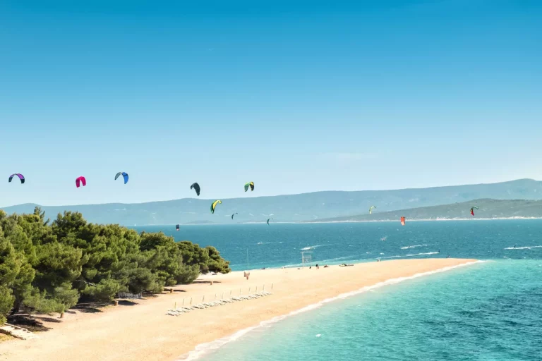 View of the landmark Golden Horn at the island Brac in Croatia. Kitesurfer and windsurfer in the background enliven the picturesque scene.